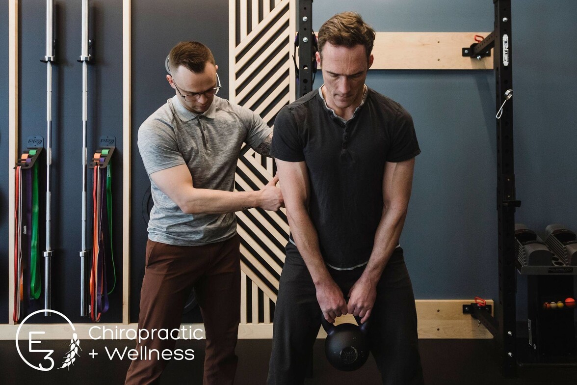 Dr. Kurtis Gryba coaching a patient on proper lifting technique, helping them return to the gym and move with confidence.